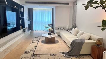 A modern living room with a sofa, coffee table, and a TV.