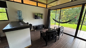 Una cocina moderna con una isla grande, un comedor con muebles negros y un amplio ventanal corredera que da a un jardín.