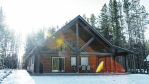 A log cabin with a large porch and a dining area.