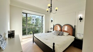 Una camera da letto con una grande finestra, un letto con testiera in legno, un comodino e una sveglia a parete.