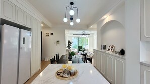 Una cucina moderna con mobili bianchi, un piano di lavoro in marmo e un'isola centrale con candele e barattoli.