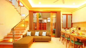 A modern living room with a sofa, dining table, and staircase. - Luxury Villa Noam 2BR Nusa Dua (Nusa Dua)