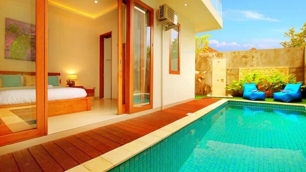 A modern bedroom with a large bed, sliding glass doors, and a view of a swimming pool. - Luxury Villa Noam 2BR Nusa Dua (Nusa Dua)
