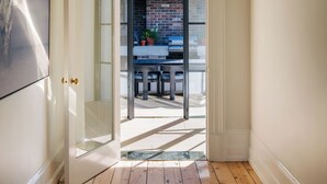 A hallway leading to an outdoor patio with a brick fireplace, a table, and chairs. - Leighton House, an unforgettable luxury farm stay in Northern Tasmania, Evandale (Western Junction)