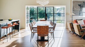 A spacious dining area with a long table and chairs, large windows, and a modern pendant light. - Leighton House, an unforgettable luxury farm stay in Northern Tasmania, Evandale (Western Junction)