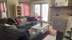 A living room with a grey sofa, a coffee table, and a TV stand. - Charming 3-bedroom house with WiFi, AC in welcoming Conyers (Conyers)