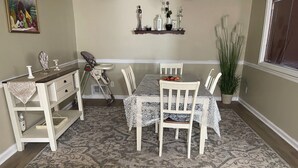 A dining area with a table set for four, surrounded by chairs. A baby stroller is positioned near the table. - Charming 3-bedroom house with WiFi, AC in welcoming Conyers (Conyers)