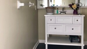 A bathroom with a white vanity, a large mirror, and a wall-mounted light fixture. - Charming 3-bedroom house with WiFi, AC in welcoming Conyers (Conyers)
