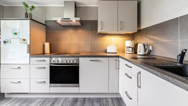 A modern kitchen with a built-in oven, a coffee maker, and a sink.