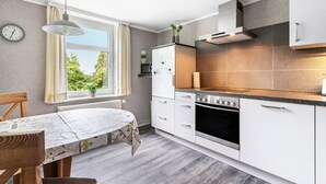 A modern kitchen with white cabinets, a built-in oven, and a window with curtains.