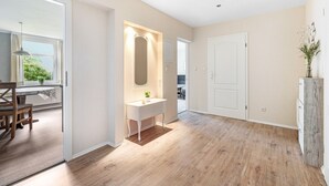 A modern interior with a wooden floor, a white vanity with a mirror, and a view of a dining area.