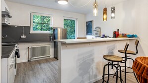 A modern kitchen with a central island, bar stools, and pendant lighting.