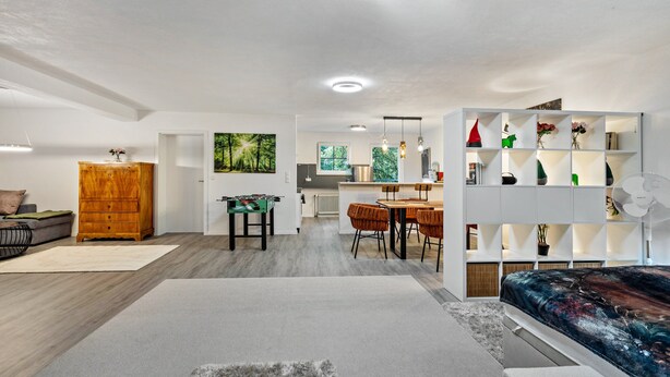A modern living room with a sofa, a coffee table, a wooden cabinet, and a dining area with chairs and a table.