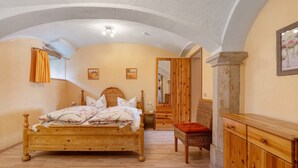 Un dormitorio con una cama y un armario de madera, una silla y un espejo.