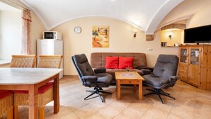 Una sala acogedora con comedor, un conjunto de sofás, un televisor y un mueble de madera.
