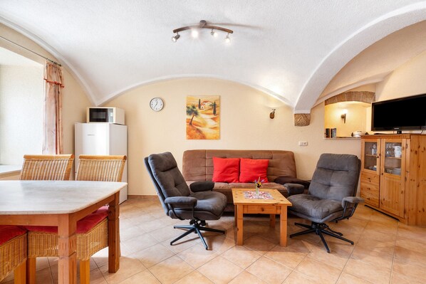 Un salon confortable comprenant un coin repas, un ensemble de canapés, un téléviseur et un meuble en bois.