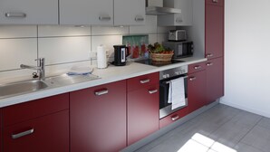 A modern kitchen with stainless steel appliances, a built-in oven, and red cabinetry. - Holiday Home 'Brise' with Private Terrace, Shared Garden and Wi-Fi (Boren)