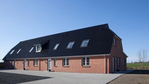 A red brick building with a sloped roof, multiple windows, and a paved driveway. - Holiday Home 'Brise' with Private Terrace, Shared Garden and Wi-Fi (Boren)