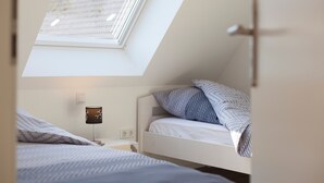A bedroom with a skylight, a bedside lamp, a bed with patterned bedding, and a nightstand. - Holiday Home 'Brise' with Private Terrace, Shared Garden and Wi-Fi (Boren)
