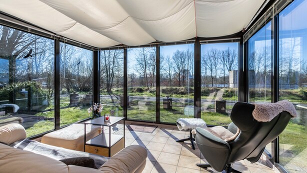 Una habitación moderna con un amplio ventanal, un sofá, un sillón y una mesita de centro.