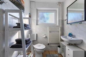 A modern bathroom with a white toilet, a sink, a towel rack, and a window.