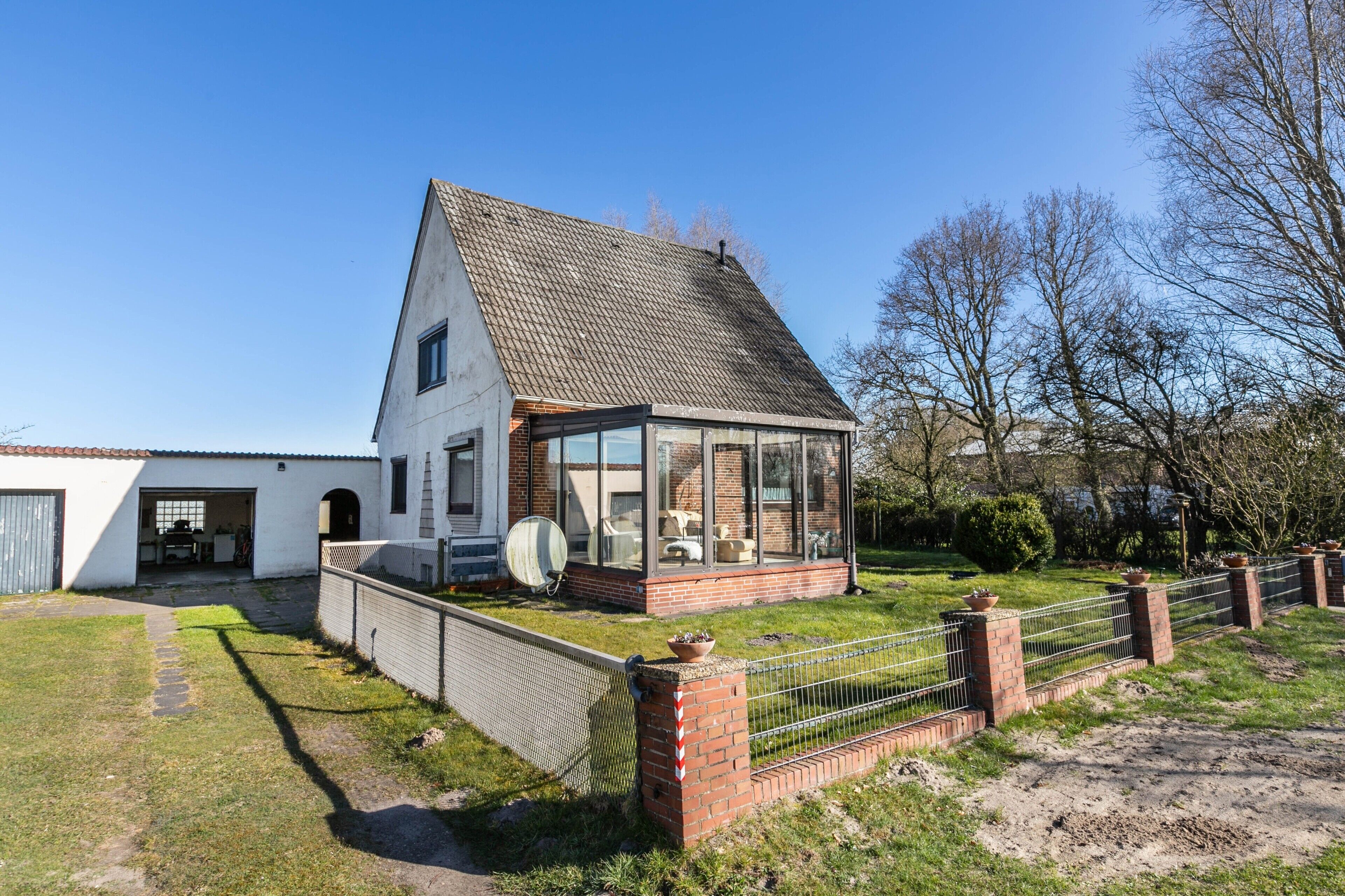 Ein Haus mit Garage, überdachter Veranda und umzäunter Garten.