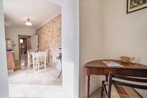 A room with a dining table, chairs, a kitchen area, and a bathroom visible through an open door. - San Giorgio Boutique Apt1 With Airco, Martano, Italy (Martano)