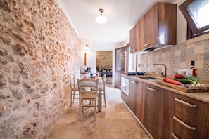 Une cuisine avec des meubles en bois, un mur en pierre et un pare-feu en carrelage.