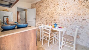 Una cocina con pared de piedra, encimera de madera y una mesa con sillas.