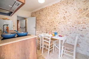 Una cocina con pared de piedra, encimera de madera y una mesa con sillas.