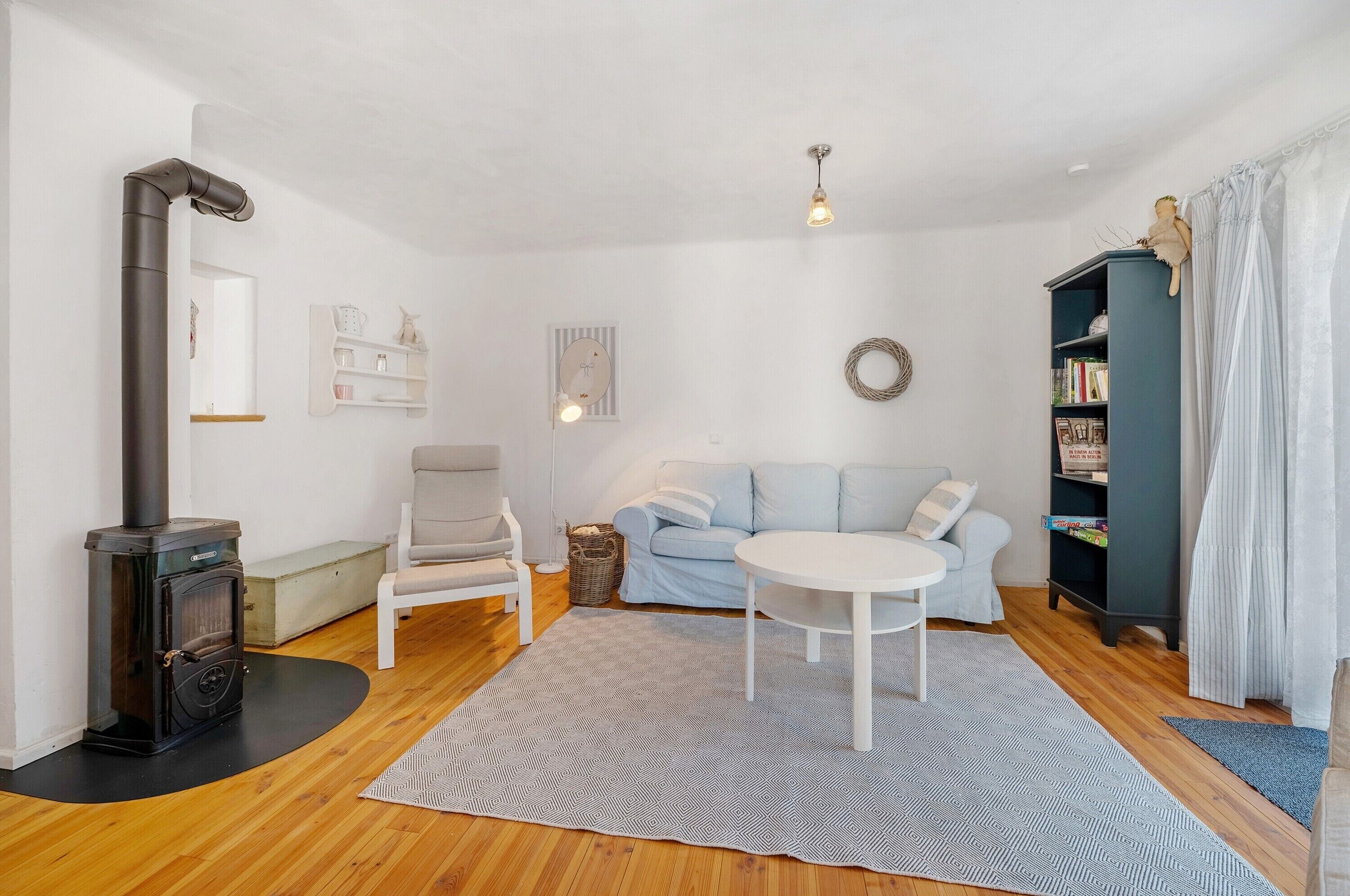 Una sala de estar con sofá, sillón, una mesa redonda y una estantería.