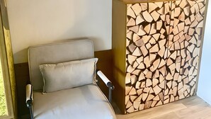 A room with a chair, a wooden wall panel, and a small shelf with decorative items.