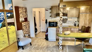 A compact kitchen with a microwave, refrigerator, and wooden cabinets.