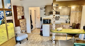 Une cuisine de taille réduite équipée d’un four à micro-ondes, d’un réfrigérateur et de meubles de rangement en bois.
