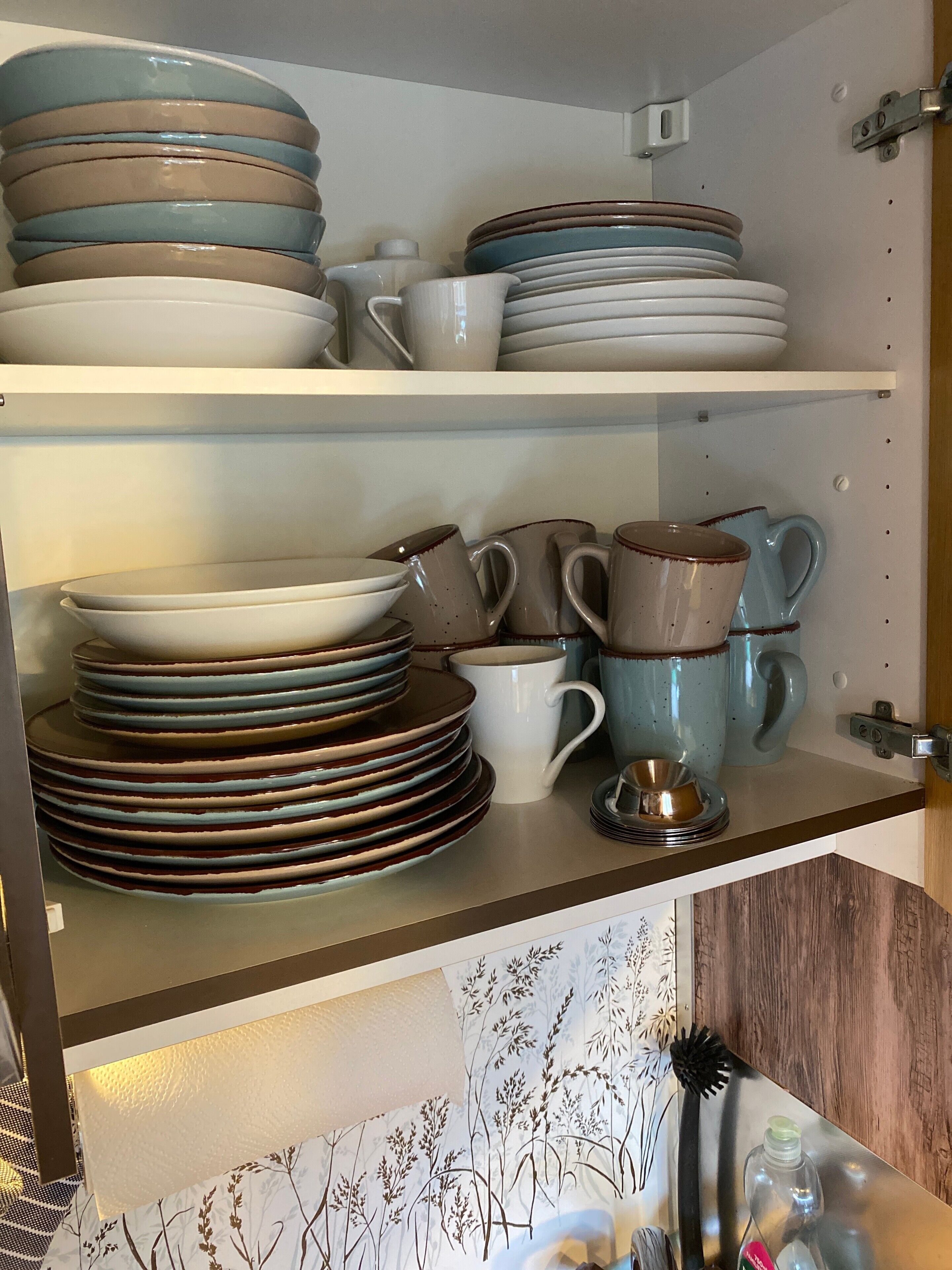 A kitchen with shelves holding plates, bowls, and mugs.