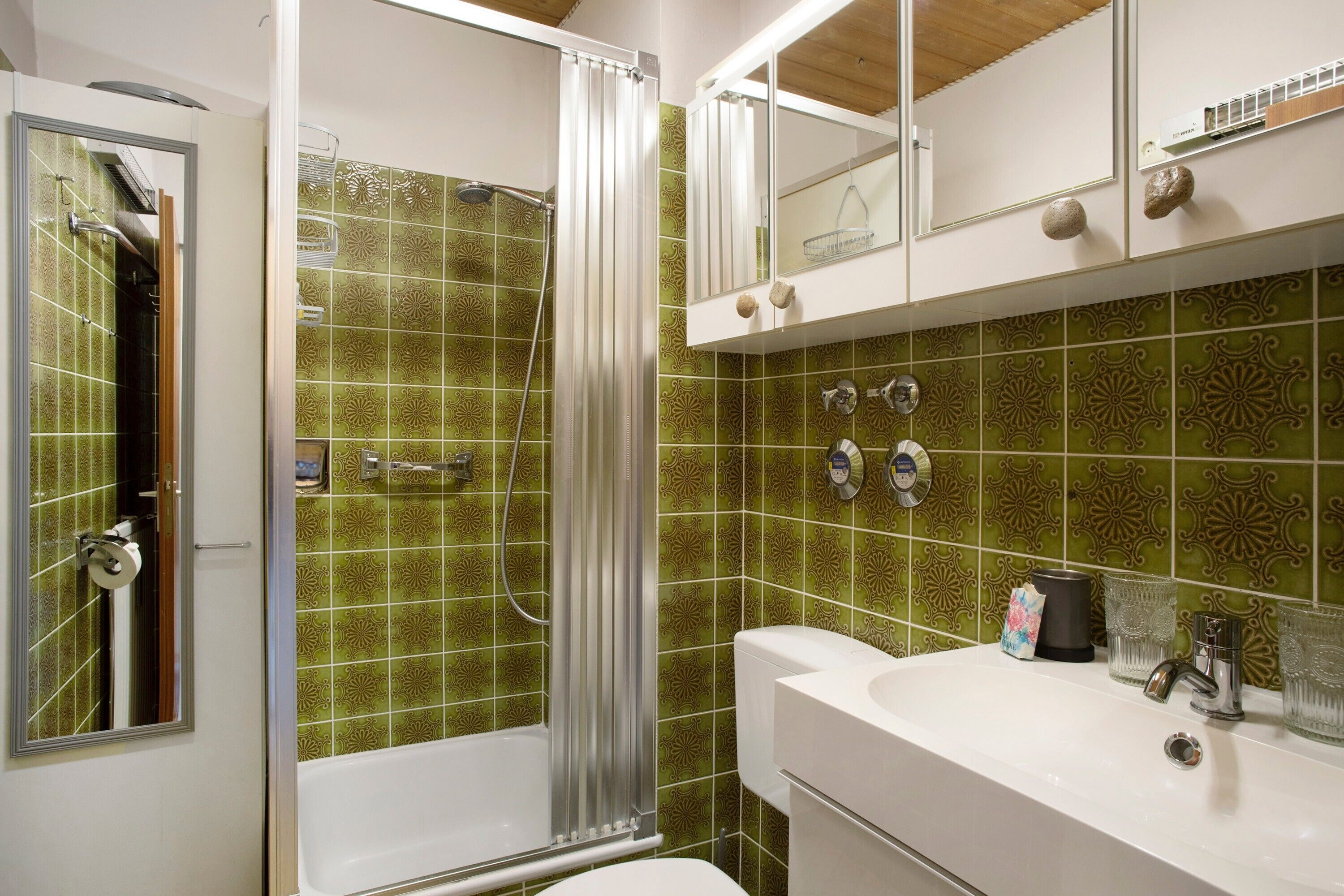 A bathroom with a shower, toilet, sink, and mirror.
