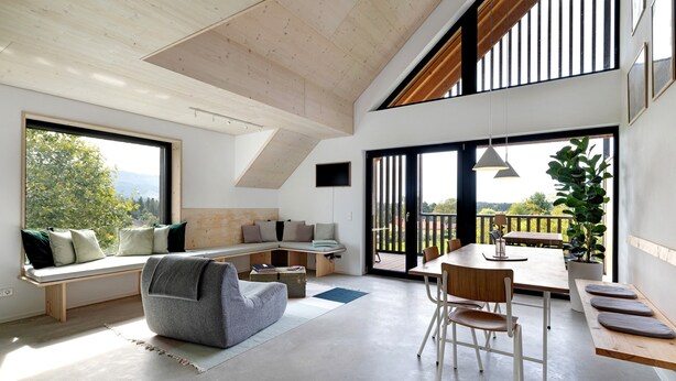 Un interior moderno con techo alto, ventanas amplias, zona de estar y comedor.