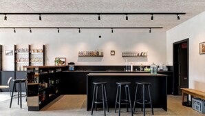 Eine moderne Bar mit einer zentralen Insel, Barhocker, Regalen mit Flaschen und einer Bank.