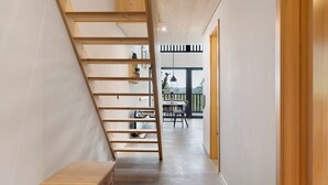 Ein modernes Interieur mit einer Holztreppe, einem Essbereich und Blick durch große Fenster.