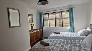 Un dormitorio con dos camas, un aparador, un espejo y una ventana con persianas.