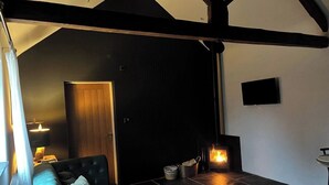 A cozy room with a fireplace, a sofa, a TV, and a door leading to another room.