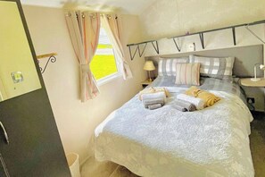 Un lit bien fait, avec des serviettes, une lampe de chevet et une fenêtre avec des rideaux.