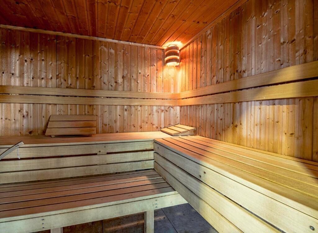 Un sauna avec des bancs en bois et un radiateur fixé au mur.