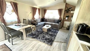 Un espacio habitable compacto con comedor, sofá, mesa de centro y kitchenette.
