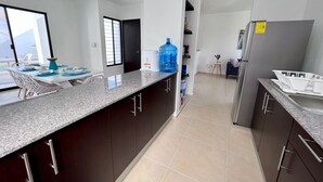 Uma cozinha moderna com armários escuros, bancada de granito e um grande dispenser de água.