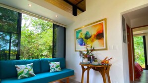 Una sala de estar moderna con un sofá color turquesa, una mesa de centro de madera y un cuadro abstracto grande en la pared.
