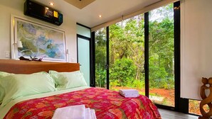Un dormitorio con una cama grande, un cuadro en la pared y vistas a zonas verdes.