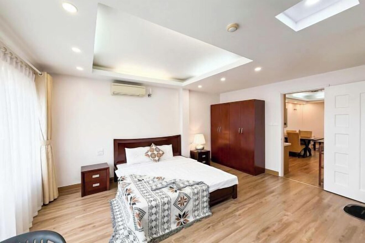 A bedroom with a bed, bedside tables, a wardrobe, and a skylight.