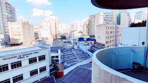 A view of a cityscape with buildings, including a white building with "FACULDADE DE EDUCAÇÃO FÍSICA PRÉDIO 20" signage. - APARTAMENTO O PREFERIDO LIBERDADE SP (São Paulo)