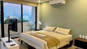 Un dormitorio moderno con una cama grande, un televisor montado en una puerta corrediza y un equipo de aire acondicionado en la pared.